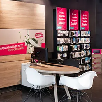 Schreibtisch mit Monitor und Stühlen in Handyshop mit Zubehörregalen