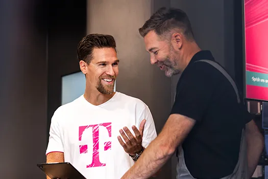 Telekom Mitarbeiter berät Kunden im Shop, beide lächeln am Tablet